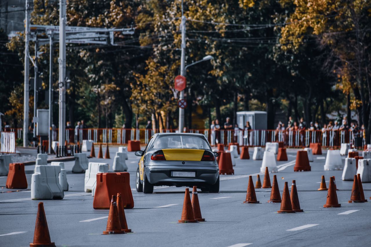 services-02 Participant in car race maneuvering between red and white traffic cones or barriers in front of audience