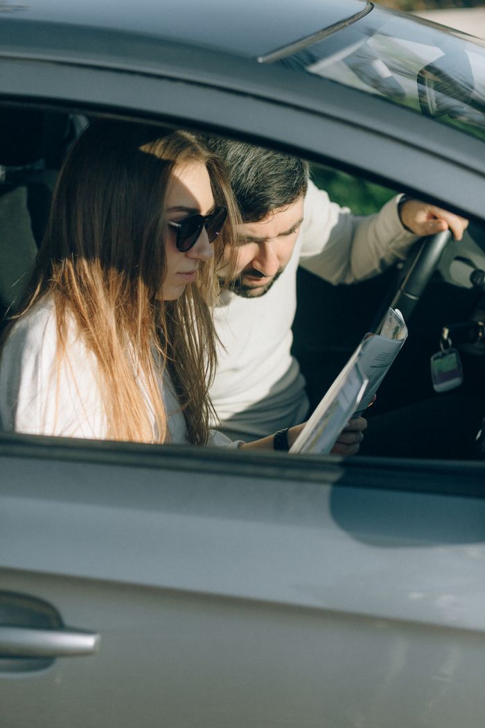 gallery-5 A young couple reading a map inside a car, planning their travel route.
