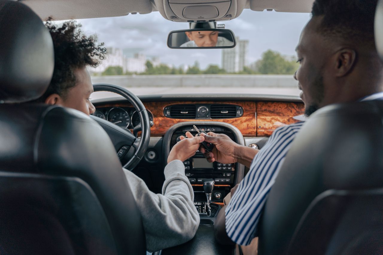 why-choose-us Father and teenage son inside car learning to drive, fostering bonding and guidance.